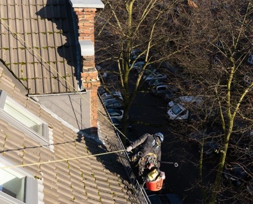 Reinigung der Dachrinne auf dem Dach mit Sicherung am Dachfenster